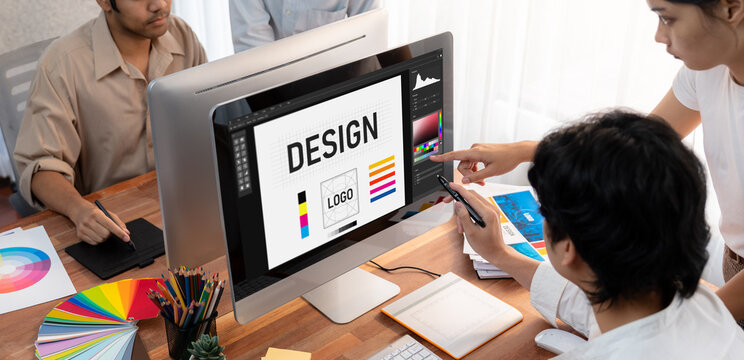 Graphic designer work on computer laptop and with graphic drawing pen while brainstorming unique design with professional graphic team in modern digital studio workplace. Panorama shot. Scrutinize