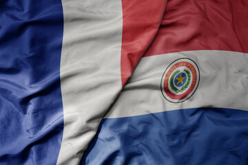 big waving realistic national colorful flag of france and national flag of paraguay .