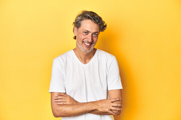 Wall Mural - Middle-aged man posing on a yellow backdrop laughing and having fun.