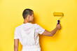 © Asier - Young female painter with yellow paint roller, studio backdrop