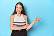 © Asier - Woman in a striped top posing on a blue studio backdrop smiling cheerfully pointing with forefinger away.