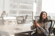 © Maria Vitkovska - Indian business woman in casual clothes, holding mobile phone while sitting at modern office