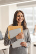 © Maria Vitkovska - Smiling confident Indian business woman holding documents looking at camera while standing at modern office. Successful business concept