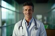 © InfiniteStudio - Portrait of friendly european doctor in workwear with stethoscope on neck posing in clinic interior, looking and smiling at camera