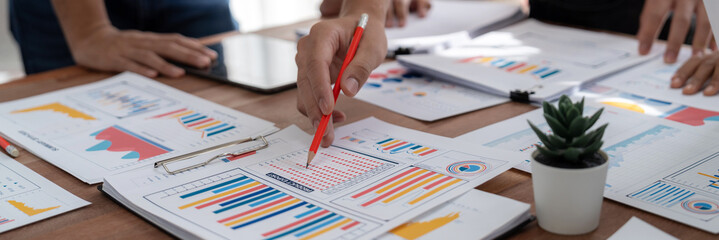 Leinwandbilder - Analyst team utilizing BI Fintech to analyze and pointing at financial dashboard paper office. Businesspeople examining report paper on table for business insight. Panorama shot. Scrutinize