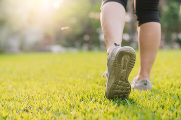 Wall Mural - jogger woman. close up person training sport runner young female shoe on grasses in public park. fitness leg and foot exercise athlete. marathon in nature. active healthy lifestyle workout concept.