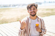 © luismolinero - Handsome Arab man with a cornet ice cream at outdoors pointing to the side to present a product