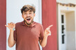 © luismolinero - Young Arabian handsome man holding home keys at outdoors surprised and pointing finger to the side