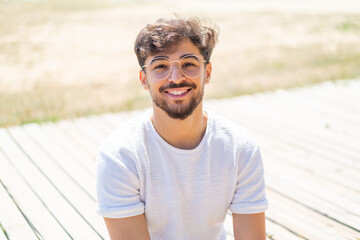 Wall Mural - Handsome Arab man at outdoors With glasses with happy expression