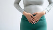 woman appears to have a stomach ache while standing on a white isolated background
