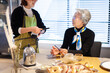 © Monet - カフェで店員と会話をするシニア女性のお客さん
