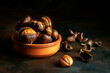 Roasted chestnuts in a clay bowl on black background. Traditional food concept. Dark low key photo. Copy space. Close-up. Selective focus, blurred background.