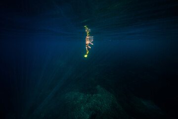 Anonymous man diving in deep blue ocean