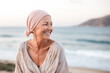 Happy mature caucasian bald confident woman in pink hat enjoying life after surviving breast cancer in sea ​​coast. Portrait of beautiful hairless girl smiling
