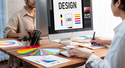 Fototapete - Graphic designer work on computer laptop and with graphic drawing pen while brainstorming unique design with professional graphic team in modern digital studio workplace. Panorama shot. Scrutinize
