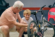 Serious Old Man Showing Boy Detail Of Bicycle