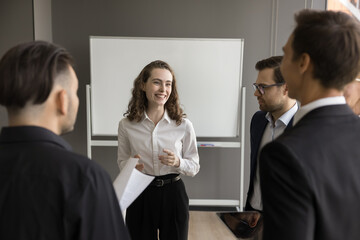 Canvas Print - Happy attractive young business representative woman talking to partners, investors on meeting, standing in office boardroom, discussing startup project, investment, partnership terms