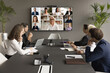 © fizkes - Cheerful mature business mentor woman training diverse office staff on video conference chat, speaking online to diverse freelancers on wall display and office workers at meeting table