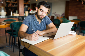 Wall Mural - Attractive man writing while doing remote freelance work