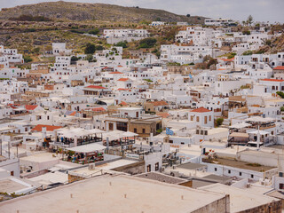 Wall Mural - Lindos town in Greece aerial view in cloud summer day, white houses in Rhodes island , cityscape viewpoint traditional greek architecture, famous landmark and touristic destination concept