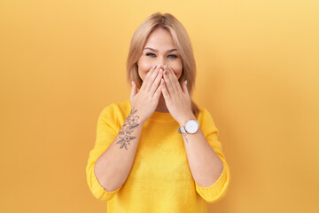 Poster - Young caucasian woman wearing yellow sweater laughing and embarrassed giggle covering mouth with hands, gossip and scandal concept