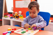 © Krakenimages.com - Adorable hispanic boy playing with maths puzzle game sitting on table at kindergarten
