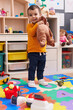 © Krakenimages.com - Adorable hispanic boy playing with dinosaur toy standing at kindergarten
