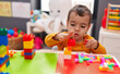 © Krakenimages.com - Adorable hispanic boy playing with construction blocks sitting on table at kindergarten