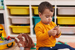 © Krakenimages.com - Adorable hispanic boy sitting on floor with relaxed expression at kindergarten