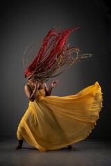 African American female in a vibrant yellow dress dancing joyfully with moving hair