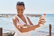© Krakenimages.com - African american woman smiling confident applying sunscreen lotion at seaside