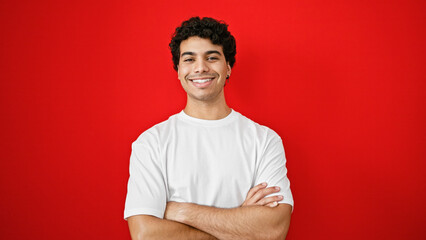 Sticker - Young latin man smiling confident standing with arms crossed gesture over isolated red background