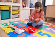 © Krakenimages.com - Adorable hispanic girl playing supermarket game sitting on floor at kindergarten