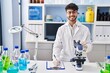 © Krakenimages.com - Young hispanic man scientist writing on document using microscope at laboratory