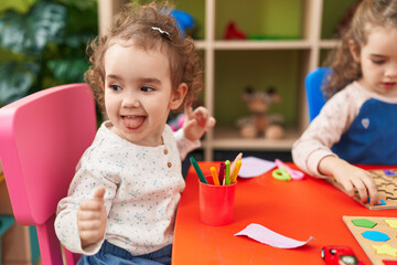 Wall Mural - Adorable girls playing with maths puzzle game sitting on table at kindergarten