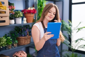 Poster - Young woman florist talking on smartphone using touchpad at florist shop