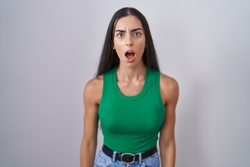 Wall Mural - Young woman standing over isolated background afraid and shocked with surprise and amazed expression, fear and excited face.