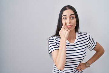 Poster - Young brunette woman wearing striped t shirt pointing to the eye watching you gesture, suspicious expression