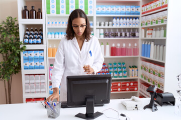 Sticker - Young african american woman pharmacist using computer holding pills bottle at pharmacy