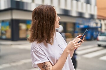 Wall Mural - Young woman using smartphone at street