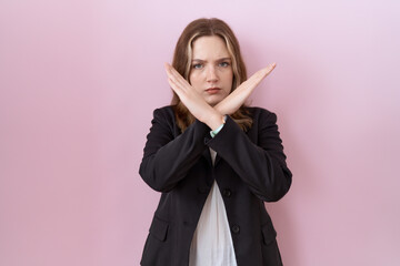 Young caucasian business woman wearing black jacket rejection expression crossing arms doing negative sign, angry face