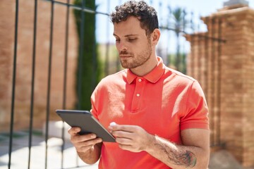 Wall Mural - Young hispanic man watching video on touchpad at street