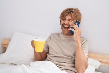 Canvas Print - Young man talking on smartphone drinking coffee at bedroom