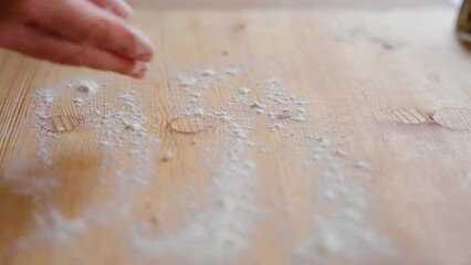 Canvas Print - Dusting a wooden work surface with flour