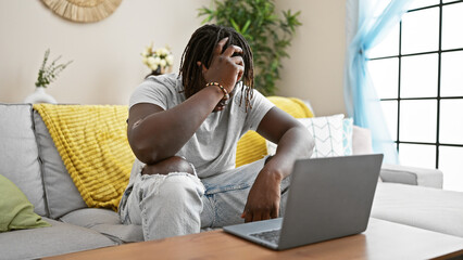 Sticker - African american man using laptop sitting on sofa stressed at home