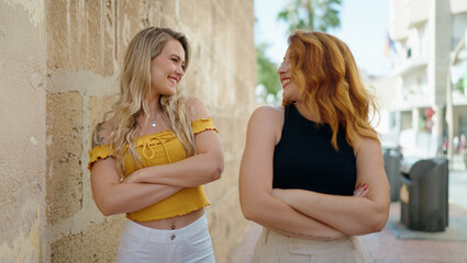 Wall Mural - Two women smiling confident standing with arms crossed gesture at street