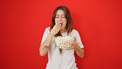 Sticker - Young beautiful hispanic woman watching drama movie eating popcorn crying over isolated red background