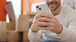 © Krakenimages.com - Young hispanic man using smartphone sitting on sofa at new home