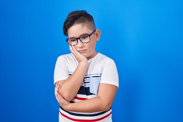 Sticker - Young hispanic kid standing over blue background thinking looking tired and bored with depression problems with crossed arms.