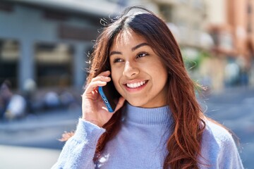 Wall Mural - Young hispanic woman smiling confident talking on the smartphone at street